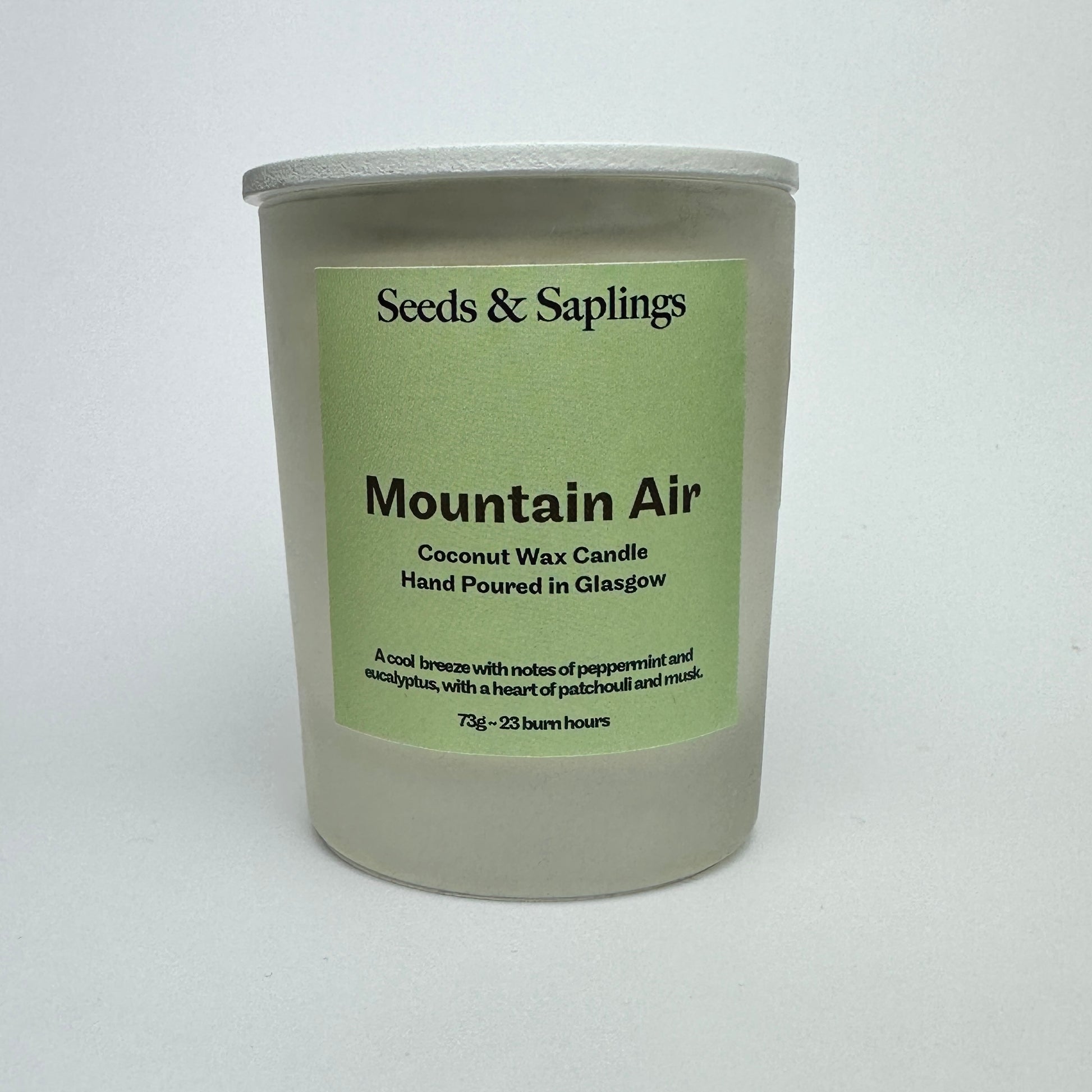 Mountain Air scented coconut wax candle in 9cl glass jar on a white surface with green label.